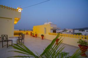 a rooftop patio with chairs and tables on a building at Rajputana Heritage Ranthambhore Home Stay in Sawāi Mādhopur