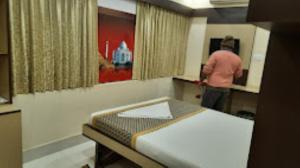 a room with a bed and a man in a room at Triumph inn Bhubaneswar in Bhubaneshwar