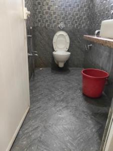 a bathroom with a toilet and a red bucket at Triumph inn Bhubaneswar in Bhubaneshwar