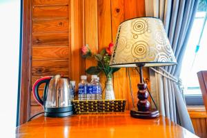 a lamp on a table with a vase of flowers at Phong Nha Escape Bungalow in Phong Nha