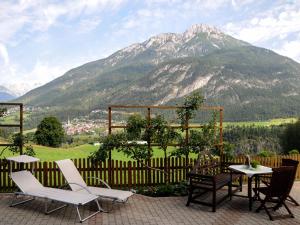 a patio with a table and chairs and a mountain at Apart Franzi in Arzl im Pitztal