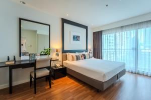 a bedroom with a bed and a desk and a desk at Somerset Park Suanplu in Bangkok