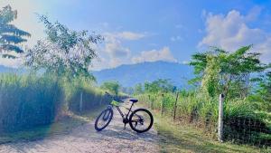 un vélo garé sur un chemin de terre à côté d'une clôture dans l'établissement HABITAS RHINO BY NATURE HUNT, à Kāziranga