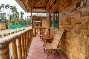 - une terrasse couverte avec des chaises et une table dans un bâtiment dans l'établissement HABITAS RHINO BY NATURE HUNT, à Kāziranga