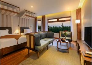 een slaapkamer met een bed, een bank en een televisie bij HA Hotel Apartments Ocean Front in Hội An