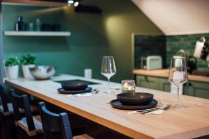 a wooden table with two glasses and plates on it at Carpathian Loft with Private Parking in Odorheiu Secuiesc +15 photos