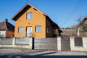ein gelbes Haus mit einem Zaun davor in der Unterkunft Cabin Home Apartment in Odorheiu Secuiesc