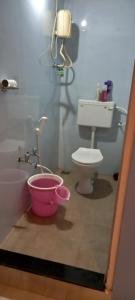a bathroom with a toilet and a pink bucket at Serene Homestay (Mini -For 2 to 3 Guest) in Panaji