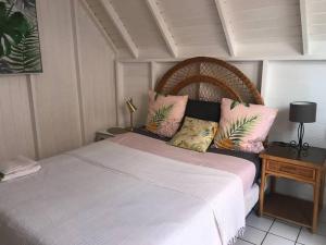 ein Schlafzimmer mit einem großen weißen Bett mit rosa Kissen in der Unterkunft Joli appartement indépendant au calme. in Marigot