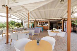an outdoor patio with tables and chairs and tablesktop at Louvre Hotel in Gouvia