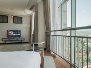 Dormitorio con balcón con cama y TV en Sanna Boutique Hotel en Arusha