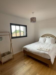 um quarto com uma cama com lençóis brancos e uma janela em Villa avec piscine chauffée em Arès