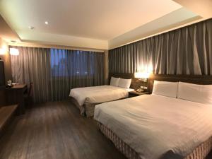 a hotel room with two beds and a window at Paris Business Hotel in Kaohsiung