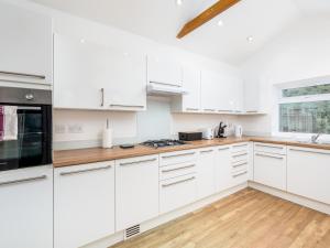 PinnerにあるFamily Friendly 3 Bed Home In Pinner Pets Welcome - Pass the Keysの白いウッドフロアのキッチン(白いキャビネット付)