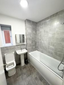 een badkamer met een bad, een toilet en een wastafel bij Fairway Villa in Stafford