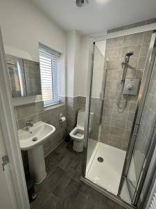 ein Bad mit einer Dusche, einem Waschbecken und einem WC in der Unterkunft Fairway Villa in Stafford