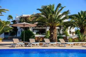uma piscina com cadeiras e um guarda-sol e palmeiras em Villa Can Ravi em Cala de Bou