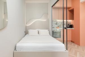 Cet appartement comprend une chambre avec un lit blanc et une cuisine. dans l'établissement Lagon Suite by Alchemia, à Thessalonique