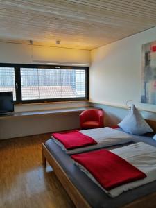 ein Bett mit einem roten Stuhl in einem Zimmer in der Unterkunft Bed & Breakfast Rotes Haus in Überlingen