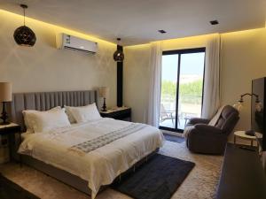 a bedroom with a bed and a chair and a window at Al Qand Chalet For Families Only in Half Moon Bay