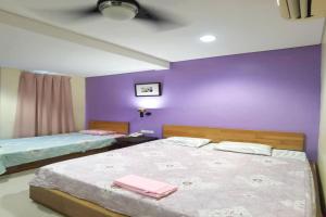 a bedroom with two beds and a purple wall at OYO 90883 Pavilion Inn Hotel in Lumut