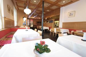 - une salle à manger avec des tables blanches, des chaises et des fleurs sur les tables dans l'établissement Hotel Post Glarnerhof, à Glarus