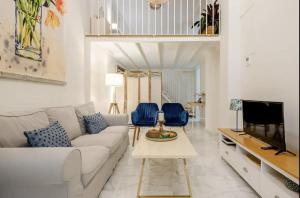 ein Wohnzimmer mit einem weißen Sofa und blauen Stühlen in der Unterkunft Loft en Centro de Sevilla con Parking in Sevilla