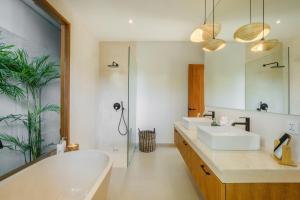 a bathroom with a tub and a sink and a mirror at Las Hermanas Villa by MAR Bali in Dalung +14 photos
