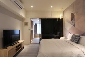 een slaapkamer met een bed en een flatscreen-tv bij Sunshine Apartment in Taipei