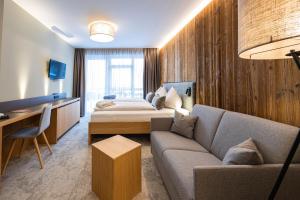 a hotel room with a couch and a bed at Hotel Der Waldhof in Zell am See