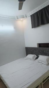 a bed in a room with a white wall at Hotel 100 Meter in Jabalpur