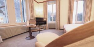um quarto de hotel com uma cama, uma cadeira e uma secretária em Hotel Post Glarnerhof em Glarus