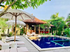 a resort with a swimming pool with chairs and an umbrella at Pondok Baruna Garden in Nusa Lembongan