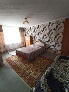 Уютная квартира в центре города في كاراغاندي: غرفة نوم بسرير وسجادة على الحائط