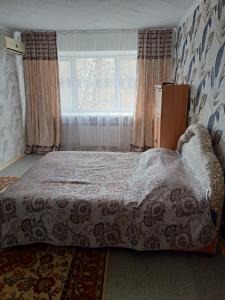 a bedroom with a bed and a large window at Уютная квартира в центре города in Karagandy