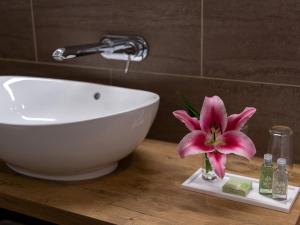ein Badezimmer mit einem Waschbecken und einer rosa Blume auf der Theke in der Unterkunft Pradas Resort Brigels in Brigels
