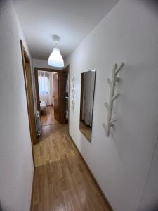 um corredor com uma parede branca e um espelho numa parede em Apartamento en Sabiñánigo para grupos con amplia y soleada terraza em Huesca