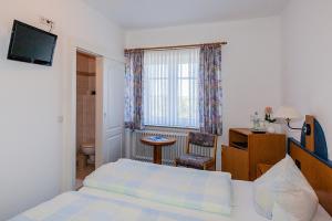 1 dormitorio con cama, escritorio y ventana en Hotel Kiek ut en Pellworm