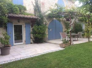 eine Terrasse mit blauen Türen und einem Tisch im Hof in der Unterkunft Authentique Mas avec piscine et pool house in Mouriès