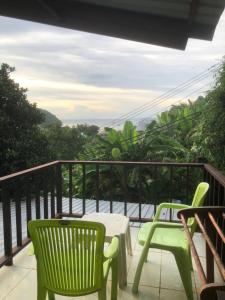 Un balcón con 2 sillas verdes y una mesa. en Phi Phi Sand Sea House, en Islas Phi Phi