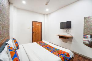 a small room with a bed and a television at FabExpress The Rawal Palace in Surat