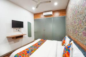 a small bedroom with a bed and a tv at FabExpress The Rawal Palace in Surat