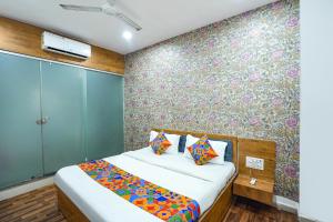 a bedroom with a bed with a floral wall at FabExpress The Rawal Palace in Surat