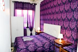a purple bedroom with a bed and purple wallpaper at Venice Rainbow Apartment San Marco in Venice