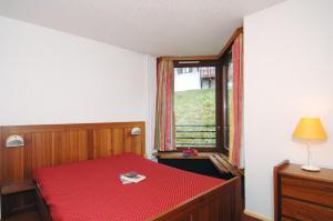 een slaapkamer met een rood bed en een raam bij Résidence Odalys Tourotel in Val Thorens