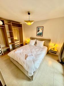 Un dormitorio con una cama grande con sábanas blancas. en AURON 2P NEUF - Le Mont d'Auron, en Auron
