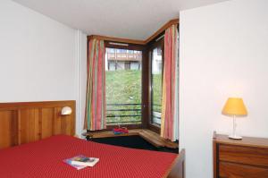 a bedroom with a window and a table with a book at Résidence Odalys Tourotel in Val Thorens +41 photos