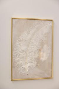 une photo d'une plume blanche dans un cadre en or dans l'établissement Enchanting Suites Salerno, à Salerne