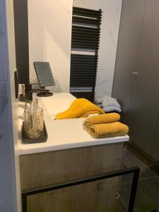 eine Badezimmertheke mit gelben Handtüchern und einem Spiegel in der Unterkunft Guestsuite The Nest in Wielsbeke