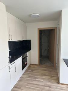 cocina con armarios blancos y encimera negra en Wohnung Neubau in Schaffhausen, en Schaffhausen